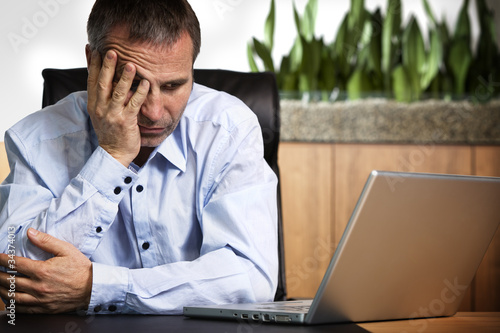 Photo: Frustrated businessman at laptop. Frustrated businessman at laptop.