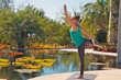 woman doing yoga outdoors in dancer variation pose side view