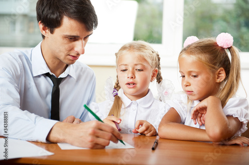 Photo: Teacher helping elementary school pupils with their tasks Teacher helping elementary school pupils with their tasks