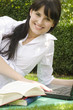 Junge Frau mit Büchern und Laptop im Garten