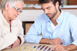 Senior woman and young man playing checkers