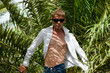 Young sexy man in sunglasses among palm trees on a windy day