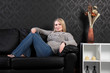 Beautiful blonde woman home on sofa in jumper