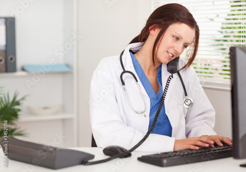 Photo: Female doctor telephoning and typing Female doctor telephoning and typing