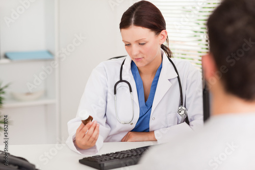 Photo: Female doctor looking at pills Female doctor looking at pills