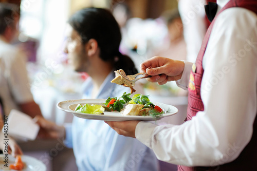 Photo: Waiter carrying a plate with meat dish Waiter carrying a plate with meat dish