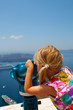 Girl looking with binoculars in Thira, Santorini, Greece