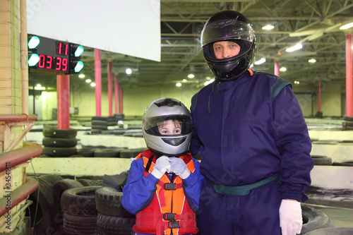 Photo: little boy and his carting trainer are standing in helmets little boy and his carting trainer are standing in helmets