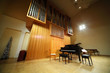 Massive wooden high pipe organ and black concert grand piano