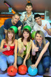 girls of squatting and three men behind with balls for bowling