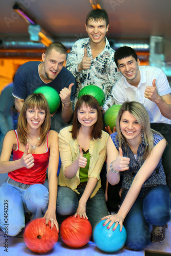 Photo: girls of squatting and three men behind with balls for bowling girls of squatting and three men behind with balls for bowling