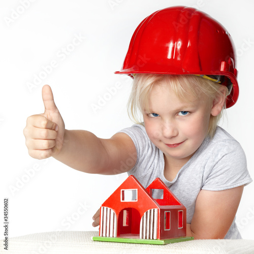 Foto: Little girl with helmet showing thump up for building a house Little girl with helmet showing thump up for building a house