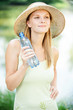 portrait of young woman wearing straw hat and holding bottle of