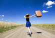 Lonely girl with suitcase at country road.