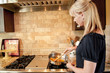Woman cooking peppers in a skillet on a gas range