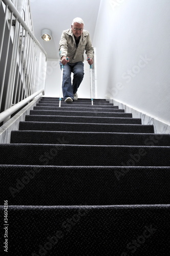 Photo: Senior mit Krücken auf einer Treppe Senior mit Krücken auf einer Treppe