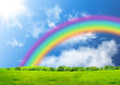 Rainbow in the blue sky over a glade
