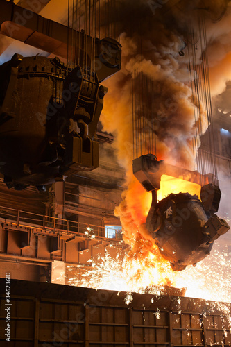 Photo: Smelting metal in metallurgical plant. Liquid iron from ladle Smelting metal in metallurgical plant. Liquid iron from ladle