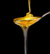 tasty honey in spoon on black background