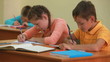 Three little children writing tests in school