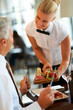 Beautiful waitress serving food to a senior man