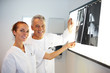 Smiling doctors examining an x-ray over light