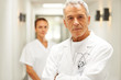 Elderly male doctor with a nurse in background