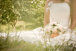 young beautiful bride with wedding bouquet on the grass