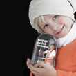 Cute little child with cap playing with snow globe in winter