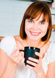 young  woman, enjoying a cup of coffee in her home.