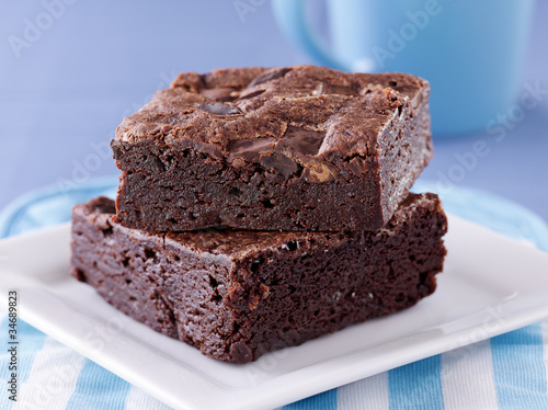 Photo: two brownies stacked on a plate. two brownies stacked on a plate.