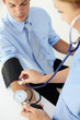 Doctor taking young man's blood pressure