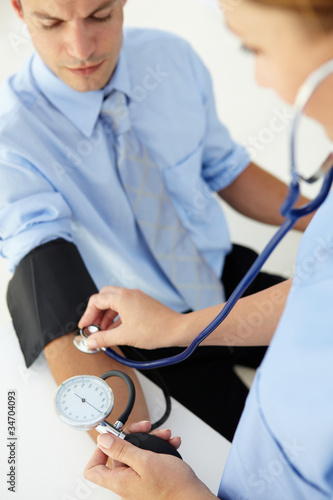 Photo: Doctor taking young man's blood pressure Doctor taking young man's blood pressure