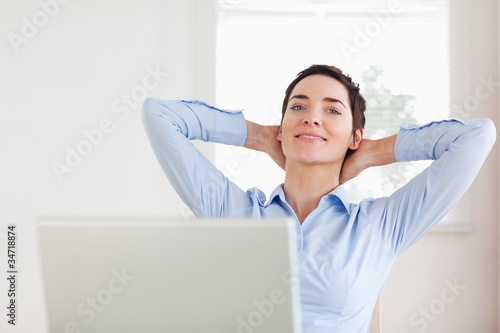 Photo: Short-haired relaxed businesswoman with a laptop looking into th Short-haired relaxed businesswoman with a laptop looking into th