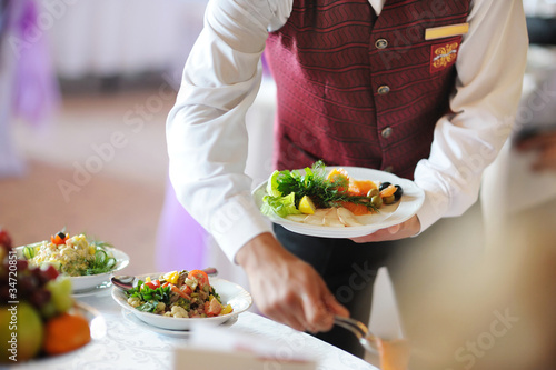 Photo: Waiter carrying a plate with meat dish Waiter carrying a plate with meat dish