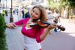 Pretty young woman with violin in the street