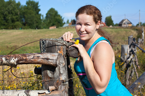 Photo: One young Caucasian Russian woman near village fence One young Caucasian Russian woman near village fence