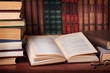 Pile of books with reading glasses on desk
