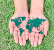 Map of the world in your hands with green grassy background