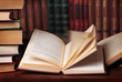 Pile of books with reading glasses on desk