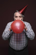 Man with party hat blowing balloon