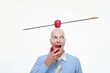 Man eating apple with apple pierced by arrow balanced on his head