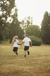 Boy and girl holding hands while running in the park