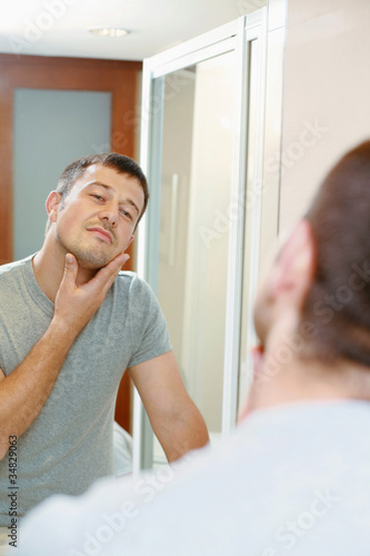 Photo: Man looking at his reflection in the mirror Man looking at his reflection in the mirror