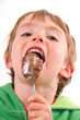 Happy boy licking chocolate off a spoon