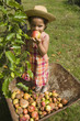Jeune fille debout dans une brouette mangeant une pomme