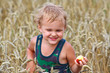 Young boy with apple on a field of wheat