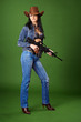 Beautiful woman in jeans with rifle on green