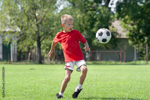 Photo: Child playing football on a soccer field Child playing football on a soccer field