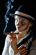 Photo: Woman in black hat with smoking cigar and gun black background Woman in black hat with smoking cigar and gun black background